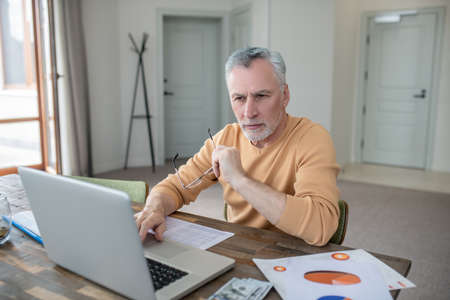 Gray-haired man working on a laptop and looking busy