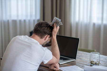 A man sitting with money in hands and looking upset