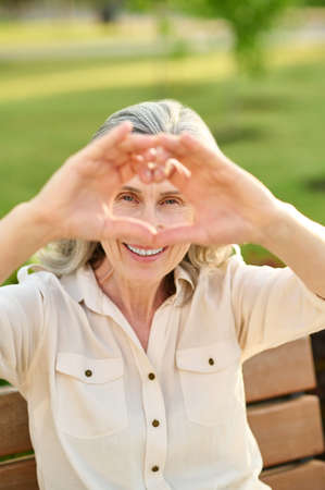 Woman showing heart with fingers outdoors