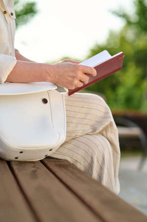 Woman reading notes sitting on bench