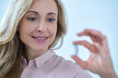Woman holding hearing aid in her fingers