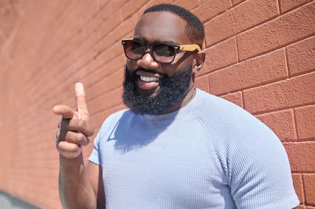 A dark-skinned man in a white tshirt and sunglasses looking confidentの写真素材