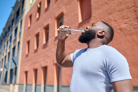 A dark-skinned man in a white tshirt walking in the streetの写真素材