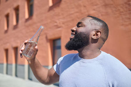 A dark-skinned man in a white tshirt walking in the streetの写真素材