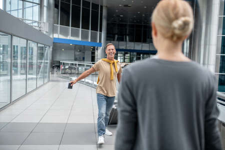 Happy man with suitcase walking towards womanの写真素材