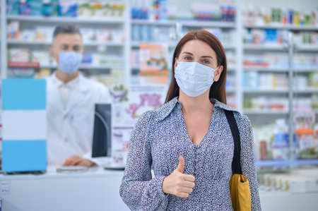 Woman in protective mask showing ok gestureの写真素材