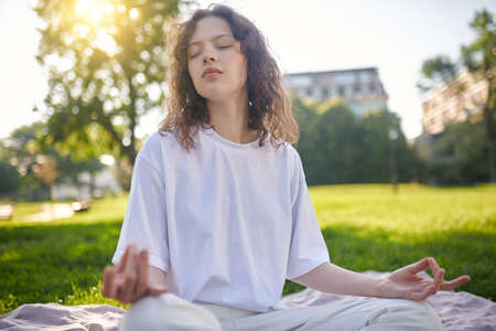 A girl in white meditating in the park and looking peacefulの写真素材