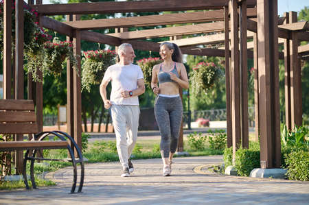A mature couple running in the park and looking contentedの写真素材