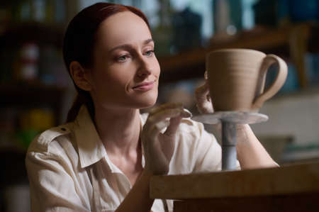 A young woman working in a pottery workshop and looking involved