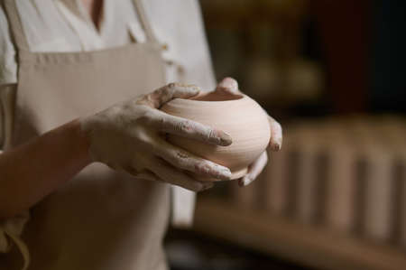 Close up of potters hands in clay and with a new bowlの写真素材