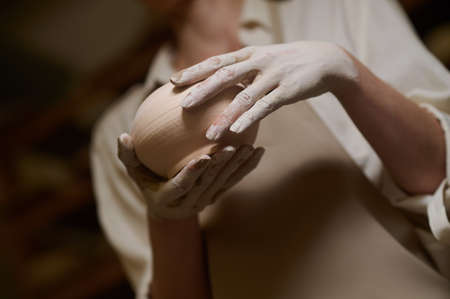 Close up of potters hands in clay and with a new bowlの写真素材
