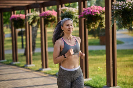 A long-haired womna in sportswear jogging in the park