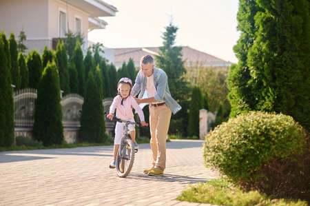 Dad teaching his daughter to ride bikeの写真素材