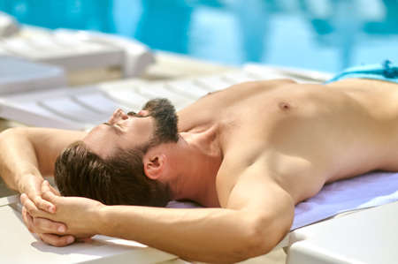 A dark-haired man sunbathing and looking relaxedの写真素材