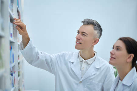 Two pharmacy employees near shelves with medicationsの写真素材