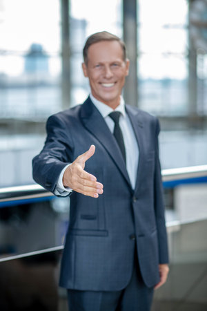 Joyful affable man holding out hand for handshakeの写真素材