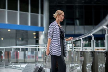 Profile of woman with suitcase waiting in airport terminalの写真素材