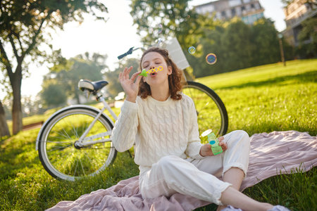 A young girl in white making bubbles and looking enjoyed