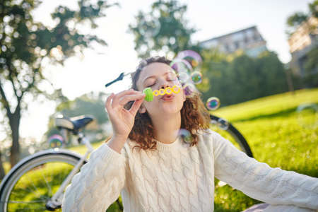 A young girl in white making bubbles and looking enjoyedの写真素材