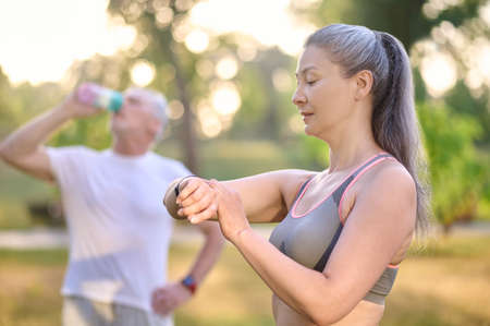 A long-haired woman looking at the watch on her wristの写真素材