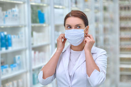 Confident woman in lab coat and protective maskの写真素材