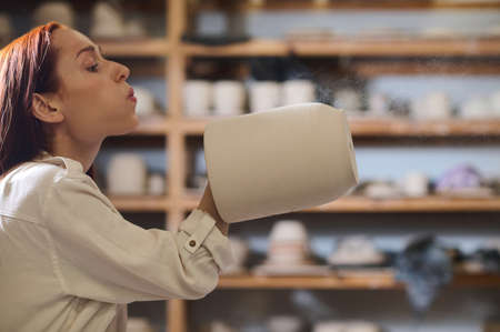A female potter blowing on a newlymade potの写真素材