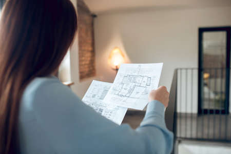 Woman with back to camera studying schemesの写真素材