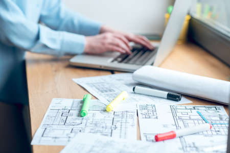 Construction plan on windowsill and female hands near laptopの写真素材