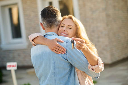 Man hugging happy woman with keysの写真素材