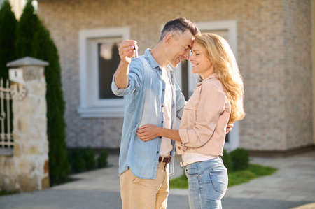 Man with key and woman standing with closed eyesの写真素材