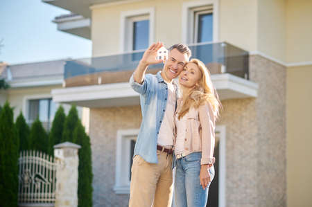 Man with house sign hugging his wifeの写真素材