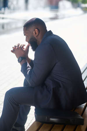 An african american man in an elegant suit sitting on the benchの写真素材