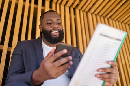 A businessman in a suit sitting on a bench with documents for analyzing in handsの写真素材