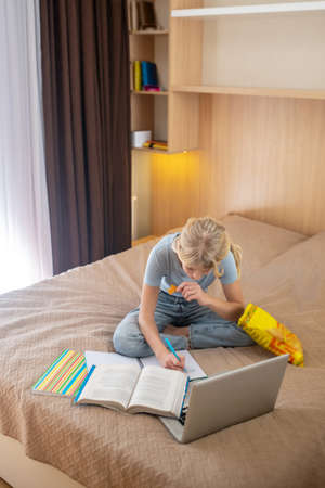 A girl lying on the bed and writing something in a notebook