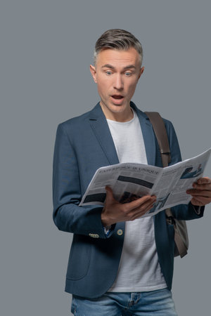 Man with open mouth reading newspaperの写真素材