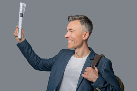 Profile of smiling man with raised newspaper in handの写真素材