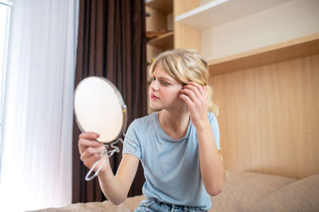 A girl looking at herself and looking unsatisfied