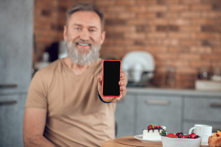 A bearded amn sitting at the table in the kitchen and looking contentedの写真素材