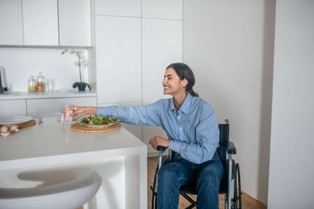 A cute girl on a wheelchair in the kitchen at homeの写真素材