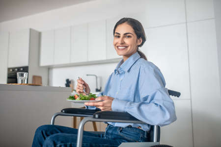 A cute girl on a wheelchair in the kitchen at homeの写真素材