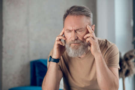 A mature bearded man suffering from a headacheの写真素材