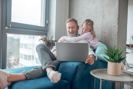 A man working while his little daughter sitting next to himの写真素材