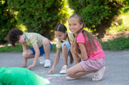 Long-haired smiling girl crouched with crayonの写真素材