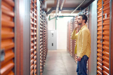 Thinking man in front of container in basementの写真素材