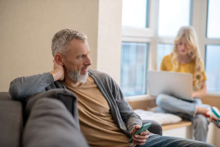 A gray-haired mature man talking on the phone and looking pleasedの写真素材