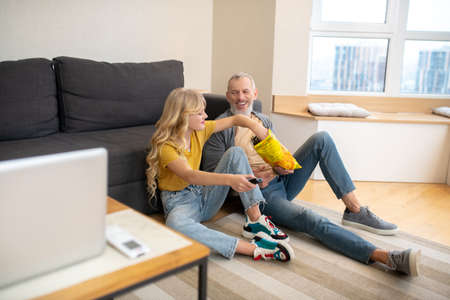 A girl and her dad sitting on the floor togetherの写真素材