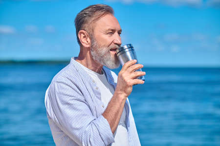 Man with drink on background of seaの写真素材