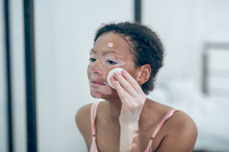 A pretty young woman cleansing her face with a spongeの写真素材