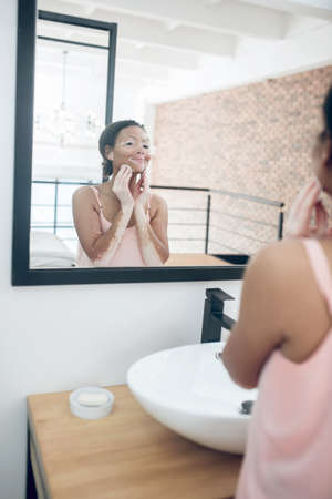 A woman in pink lingerie in a bathroom while doing beauty procedures