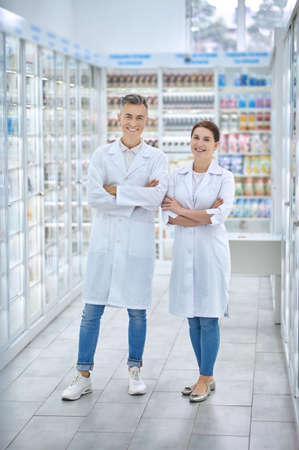 Smiling man and woman standing in pharmacyの写真素材